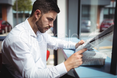 Businessman reading newspaper in office