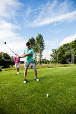 Male instructor assisting woman in learning golf