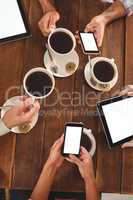 Group of friends using mobile phone while having cup of coffee