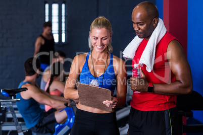 Smiling fitness instructor discussing with man in gym