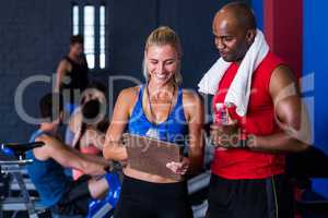 Smiling fitness instructor discussing with man in gym