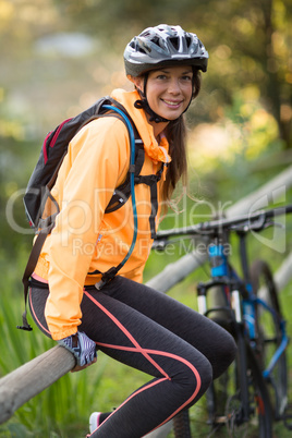 Female biker sitting on fence in countryside Female biker sitting on a fence in countryside