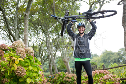Male cyclist carrying mountain bike