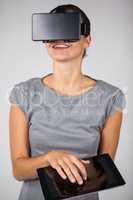 Woman holding digital tablet and using virtual reality headset