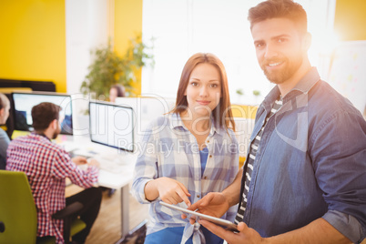 Portrait of confident business people using tablet computer at creative office