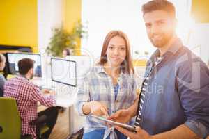 Portrait of confident business people using tablet computer at creative office