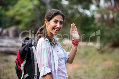 Female hiker waving hand while walking in forest