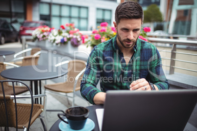 Businessman using laptop while having a cup of coffee