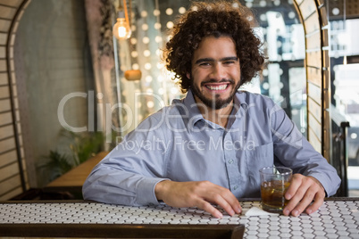 Man sitting on bar counter with glass of whisky