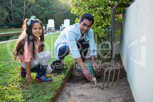 Father and daughter planting a tree in garden at backyard