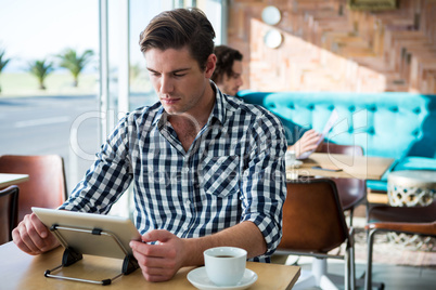 Man using digital tablet in coffee shop