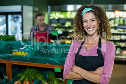 Smiling female staff standing with arms crossed in organic section