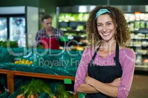 Smiling female staff standing with arms crossed in organic section