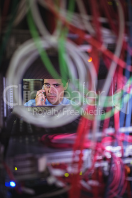 Technician talking on mobile phone while checking cables