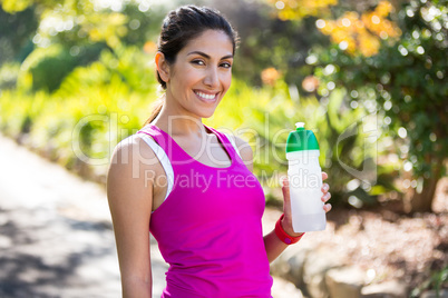Smiling jogger drinking water while taking a break