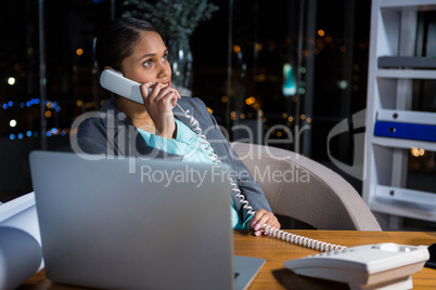 Businesswoman talking on phone while working in office