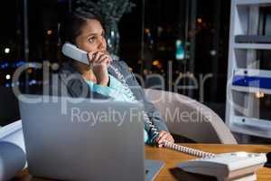 Businesswoman talking on phone while working in office