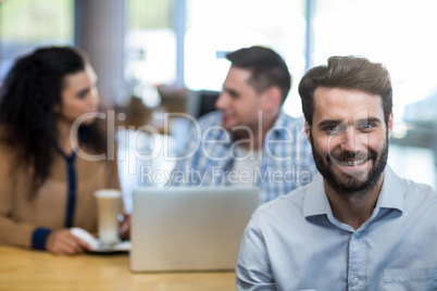 Smiling man in cafÃ?Â© with friends in background