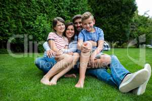 Happy family sitting on grass in park on a sunny day