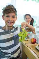 Boy holding a bunch of grapes while having breakfast