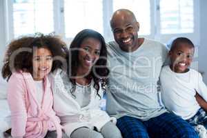 Portrait of happy family sitting on bed