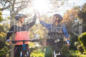 Biker couple giving high five while riding bicycle in countryside
