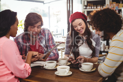 Group of friends using mobile phone and digital tablet