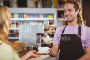 Waiter serving a cup of coffee at counter