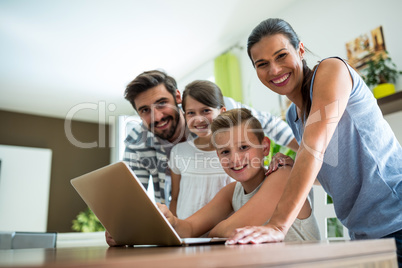 Portrait of happy family using laptop in the living room