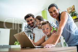 Portrait of happy family using laptop in the living room