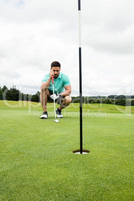 Man squatting to line up his putt