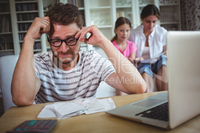 Worried man sitting at table with bills and laptop