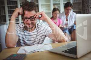 Worried man sitting at table with bills and laptop