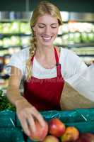 Female staff packing fruits in paper bag at supermarket