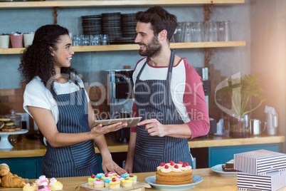 Smiling waiter and waitress using digital tablet at counter