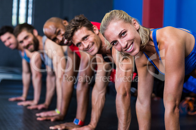 Portrait of smiling people doing push-ups in gym