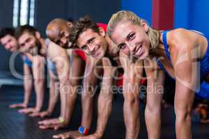 Portrait of smiling people doing push-ups in gym