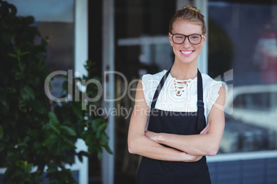 Portrait of smiling waitress standing with arms crossed