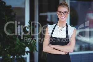 Portrait of smiling waitress standing with arms crossed