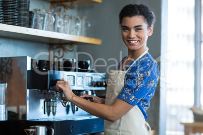 Smiling waitress making cup of coffee in cafe