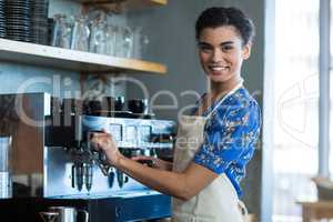 Smiling waitress making cup of coffee in cafe