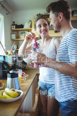 Smiling couple preparing watermelon smoothie in kitchen