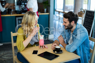 Couple interacting while having a cup of coffee and milkshake