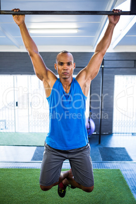 Male athlete doing chin-ups in gym