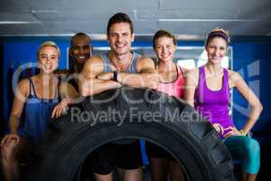 Portrait of smiling friends with tire in gym