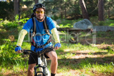 Portrait of male mountain biker with bicycle in the forest