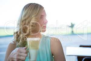 Beautiful woman holding a glass of coffee and looking sideways