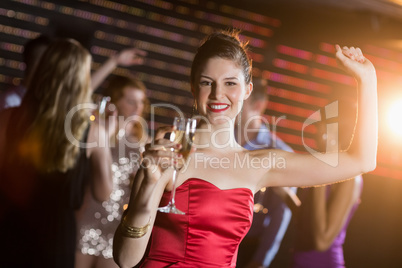 Portrait of young woman holding a glass of champagne while dancing