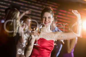 Portrait of young woman holding a glass of champagne while dancing