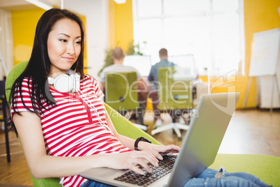 Happy executive using laptop at creative office